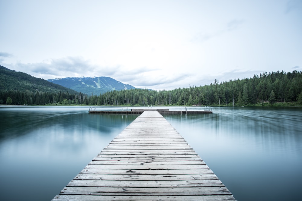 A wooden dock extending into a calm lake, surrounded by forest and mountains — the canonical LLaVA demo image